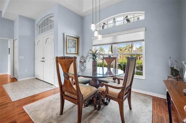 dining room featuring light hardwood / wood-style flooring and a high ceiling