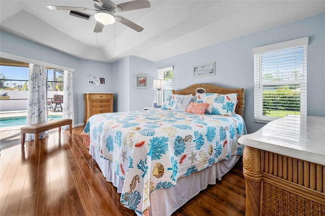 bedroom with multiple windows, dark wood-type flooring, access to outside, and a tray ceiling