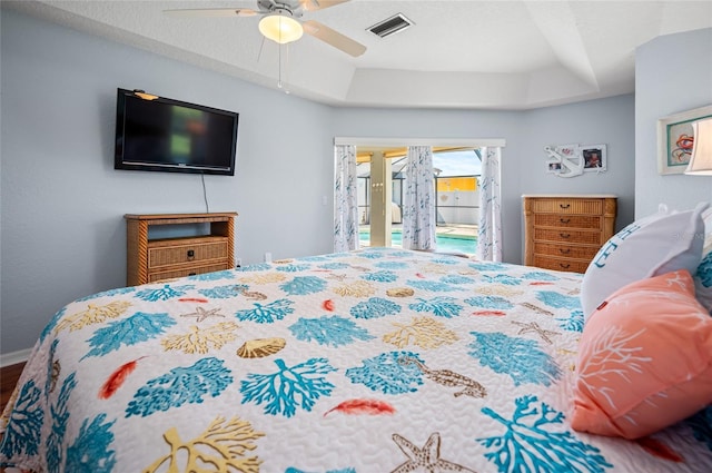 bedroom featuring access to exterior, a tray ceiling, and ceiling fan