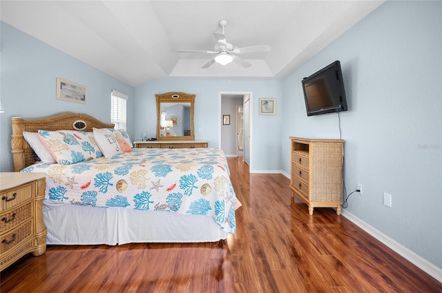 bedroom with ceiling fan, a tray ceiling, and dark hardwood / wood-style flooring