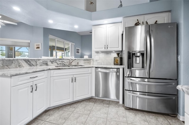 kitchen featuring sink, white cabinetry, stainless steel appliances, tasteful backsplash, and light stone countertops