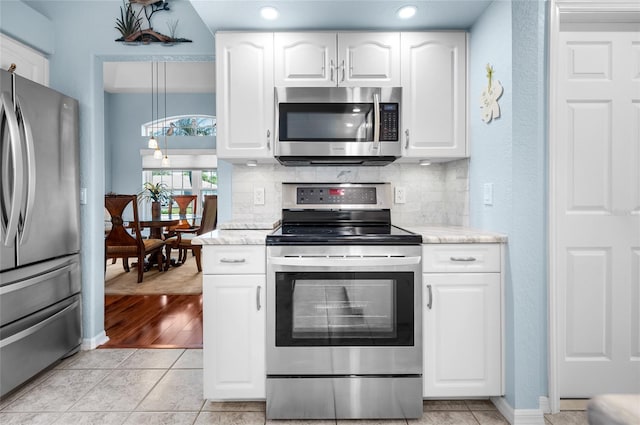 kitchen featuring backsplash, stainless steel appliances, white cabinets, and light tile patterned flooring