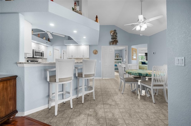 kitchen with white cabinetry, a kitchen breakfast bar, light tile patterned floors, ceiling fan, and kitchen peninsula