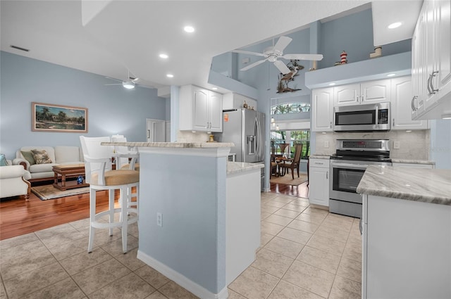 kitchen with stainless steel appliances, white cabinetry, a breakfast bar area, and light tile patterned flooring