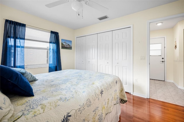 bedroom featuring multiple windows, hardwood / wood-style flooring, ceiling fan, and a closet