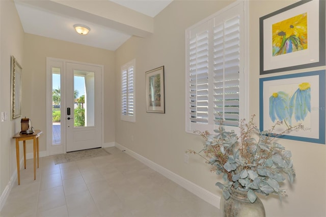 tiled foyer featuring beam ceiling