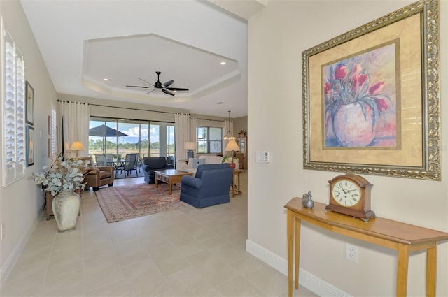 living room featuring a raised ceiling and ceiling fan