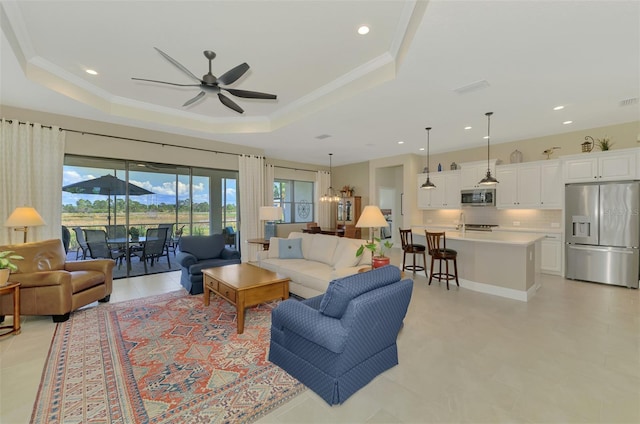 living room with a raised ceiling, crown molding, and ceiling fan