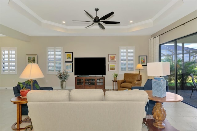 living room with ornamental molding, light tile patterned floors, ceiling fan, and a tray ceiling