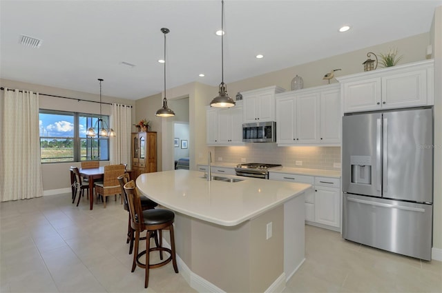 kitchen with a kitchen island with sink, sink, white cabinets, and appliances with stainless steel finishes