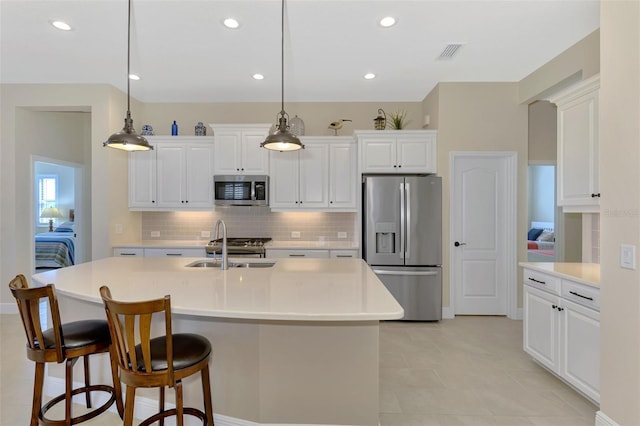 kitchen with hanging light fixtures, appliances with stainless steel finishes, and a kitchen island with sink