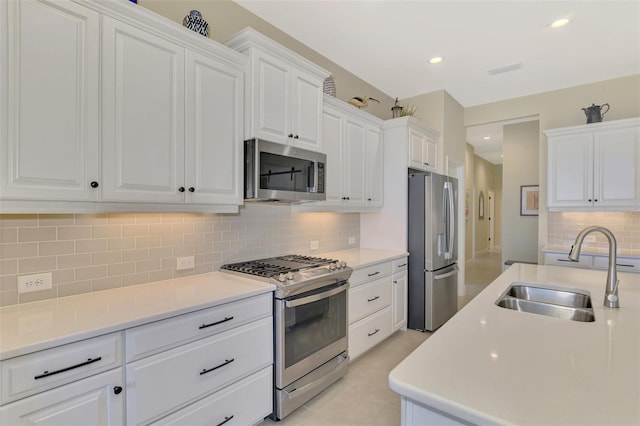 kitchen featuring light tile patterned flooring, white cabinetry, sink, decorative backsplash, and stainless steel appliances