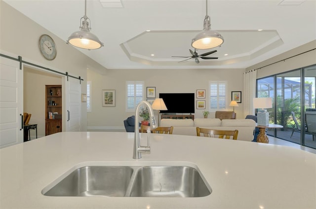 kitchen featuring pendant lighting, sink, a tray ceiling, and a barn door