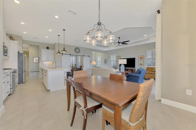 tiled dining room featuring a raised ceiling and ceiling fan