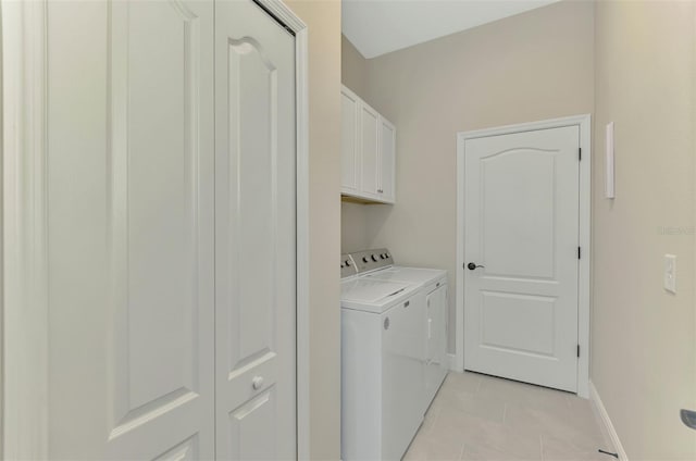 clothes washing area with cabinets, separate washer and dryer, and light tile patterned floors