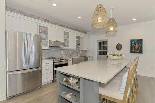 kitchen with appliances with stainless steel finishes, decorative light fixtures, white cabinetry, a breakfast bar area, and a center island