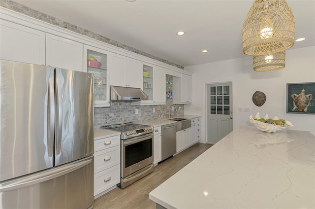 kitchen with appliances with stainless steel finishes, white cabinets, backsplash, and decorative light fixtures