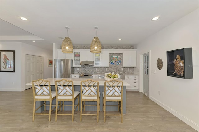 kitchen featuring a large island, white cabinetry, stainless steel appliances, and a kitchen breakfast bar