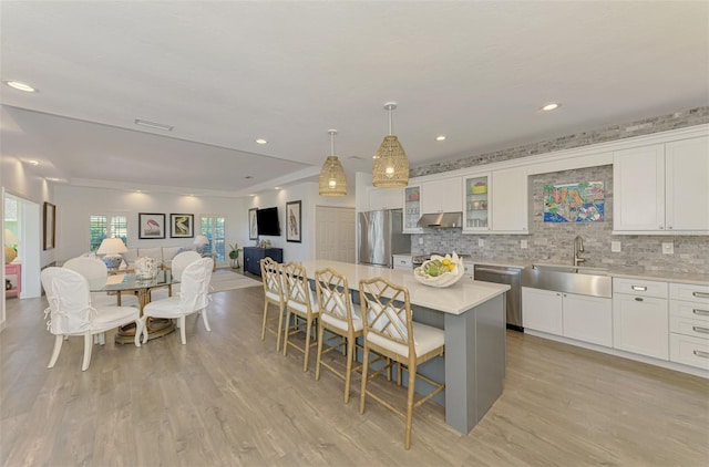 kitchen featuring sink, a kitchen breakfast bar, a kitchen island, stainless steel appliances, and white cabinets