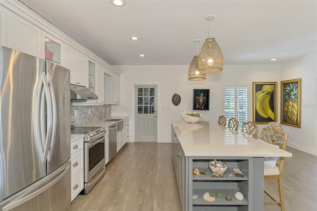 kitchen with sink, white cabinetry, decorative light fixtures, a center island, and stainless steel appliances