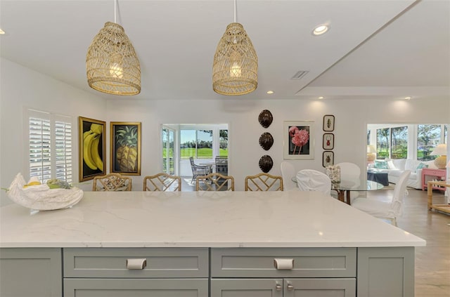 kitchen featuring gray cabinetry, decorative light fixtures, and a wealth of natural light