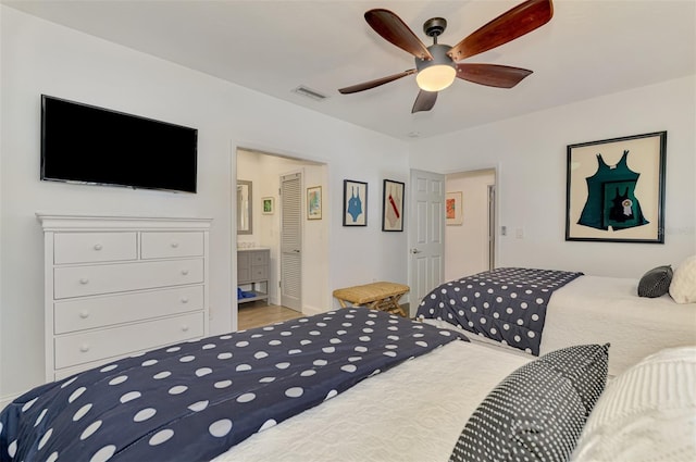 bedroom featuring wood-type flooring, ceiling fan, and ensuite bath