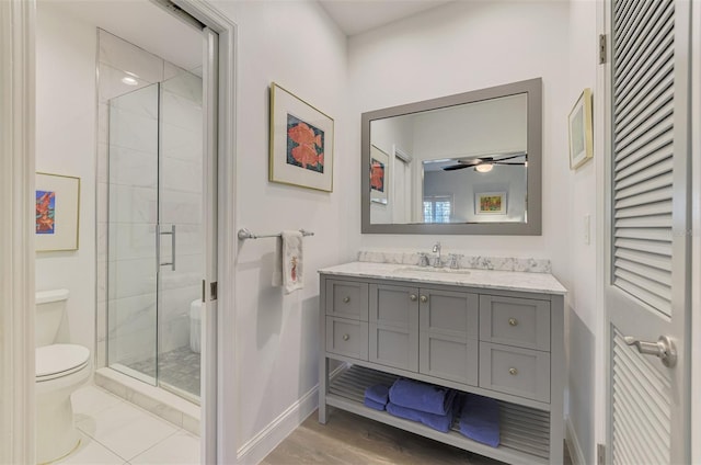 bathroom featuring ceiling fan, vanity, toilet, and a shower with door