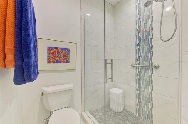 bathroom featuring a shower with shower door and toilet