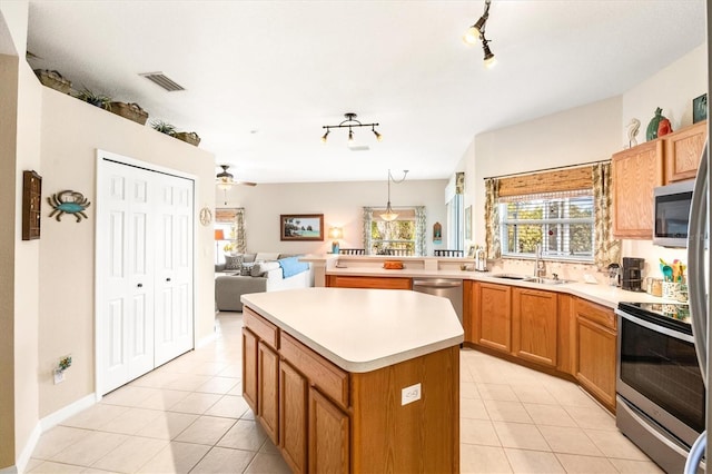 kitchen with light tile patterned flooring, sink, a center island, pendant lighting, and stainless steel appliances