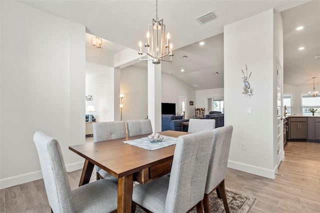 dining space featuring vaulted ceiling, light hardwood / wood-style floors, and a notable chandelier