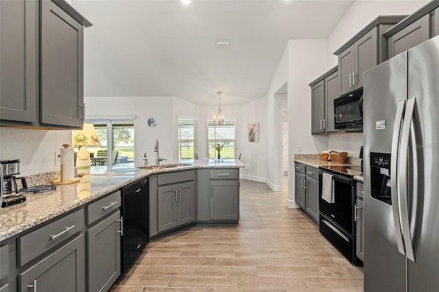 kitchen featuring sink, gray cabinetry, light stone counters, decorative light fixtures, and black appliances