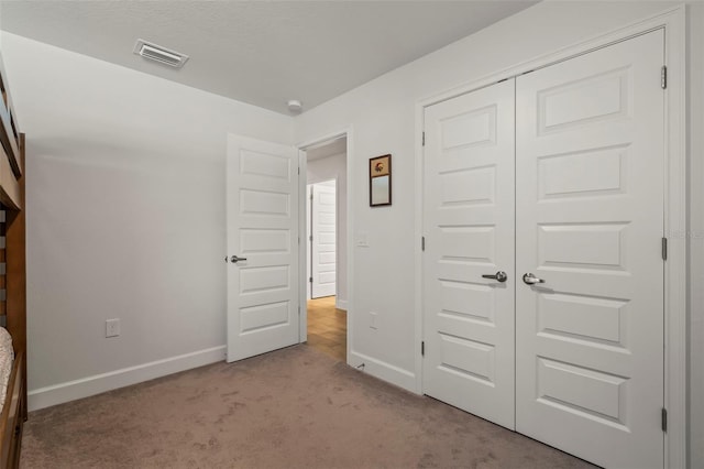 unfurnished bedroom with light carpet, a closet, and a textured ceiling