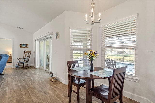 dining room with lofted ceiling, hardwood / wood-style floors, and a notable chandelier