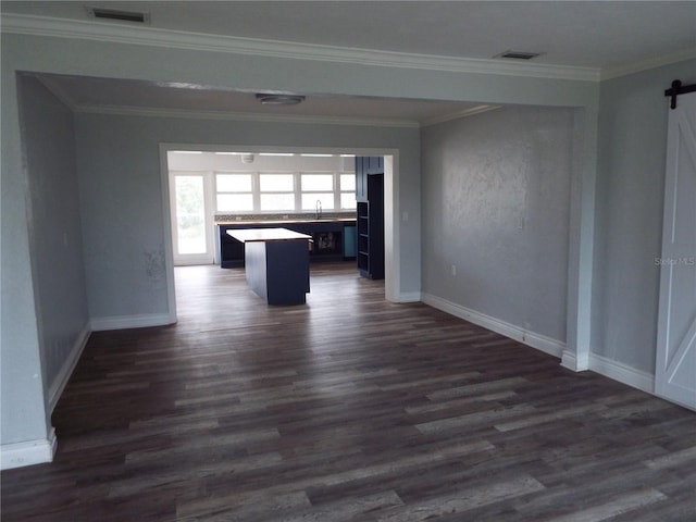 unfurnished living room with sink, dark wood-type flooring, ornamental molding, and a barn door