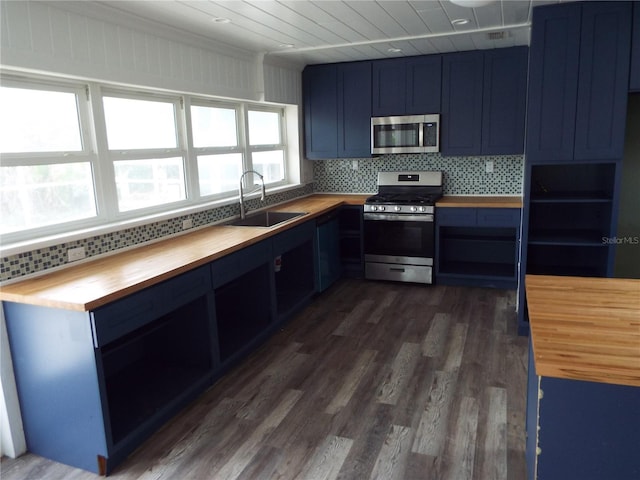 kitchen with sink, wooden counters, appliances with stainless steel finishes, blue cabinets, and decorative backsplash