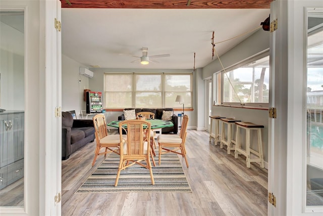 dining room featuring ceiling fan, a wall mounted AC, and light hardwood / wood-style floors