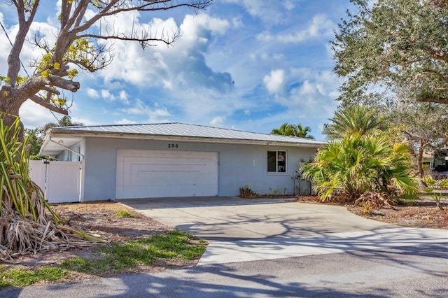 exterior space featuring a garage, concrete driveway, metal roof, and stucco siding