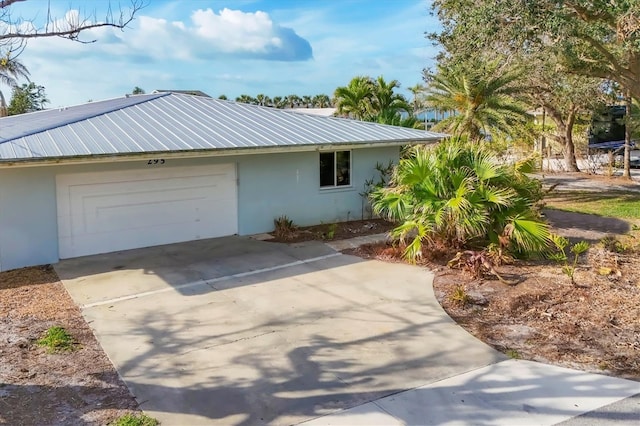 exterior space featuring a garage, concrete driveway, metal roof, and stucco siding