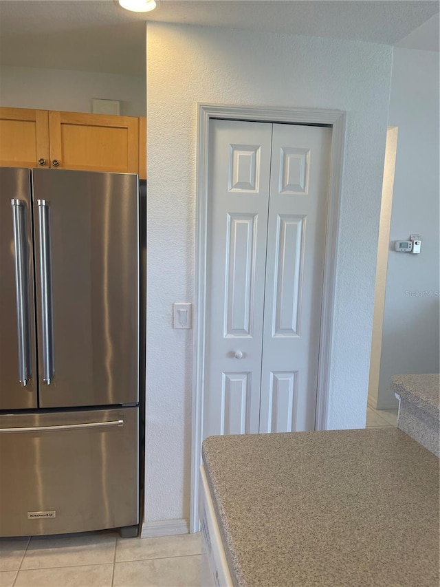 kitchen with light brown cabinetry, light tile patterned floors, and stainless steel refrigerator