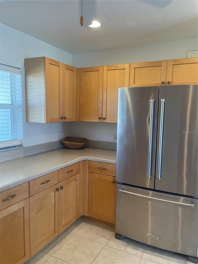 kitchen with high end fridge, light tile patterned floors, and light brown cabinetry