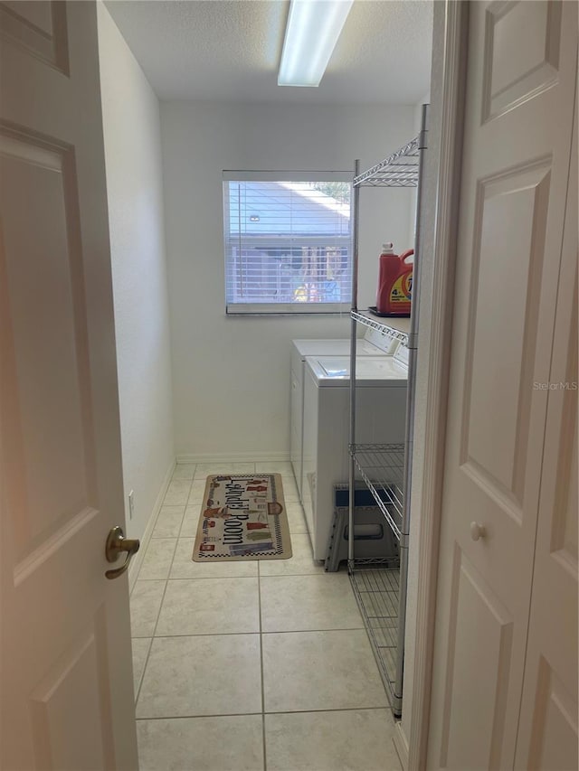 washroom featuring a textured ceiling, washing machine and clothes dryer, and light tile patterned flooring