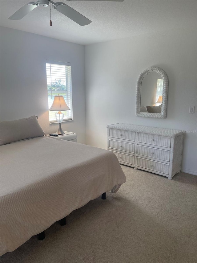 bedroom with light colored carpet, a textured ceiling, and ceiling fan