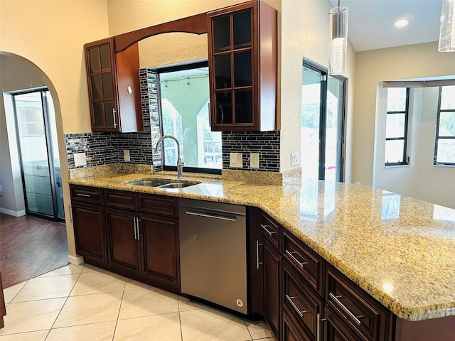 kitchen featuring pendant lighting, dishwasher, sink, light tile patterned floors, and light stone countertops