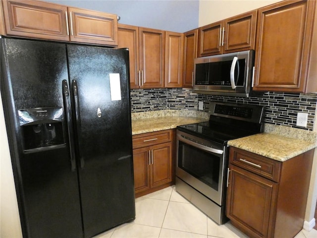 kitchen with light stone counters, light tile patterned floors, tasteful backsplash, and appliances with stainless steel finishes