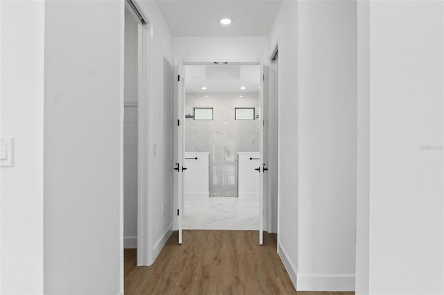 corridor featuring light wood-type flooring, baseboards, and recessed lighting