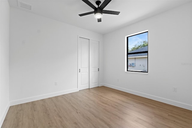 unfurnished bedroom with baseboards, ceiling fan, a closet, and light wood-style floors