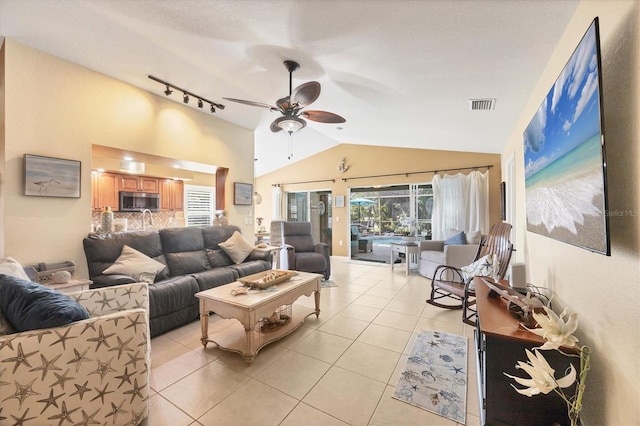 tiled living room featuring lofted ceiling, track lighting, and ceiling fan