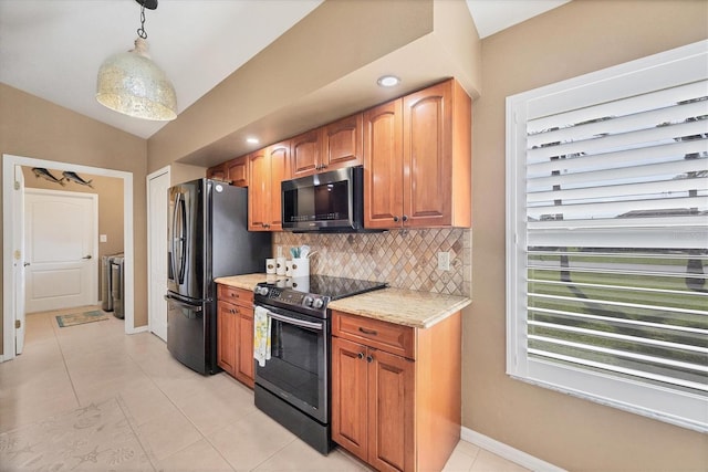 kitchen with decorative light fixtures, lofted ceiling, washing machine and clothes dryer, black fridge, and stainless steel electric range