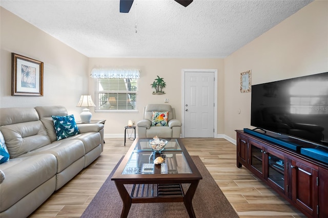 living room featuring a textured ceiling, ceiling fan, and light wood-type flooring