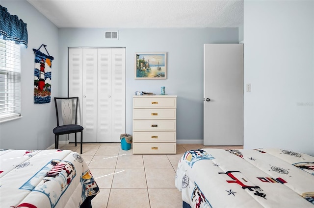 tiled bedroom with a closet and a textured ceiling